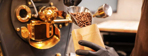 roaster manually scooping roasted beans into a coffee bag
