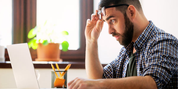 man looking at disbelief at computer to represent the high cost of coffee roasting equipment