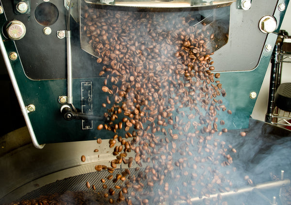 image of roasted coffee beans falling out of coffee roaster as header for Coffee Equipment Pros' FAQ page