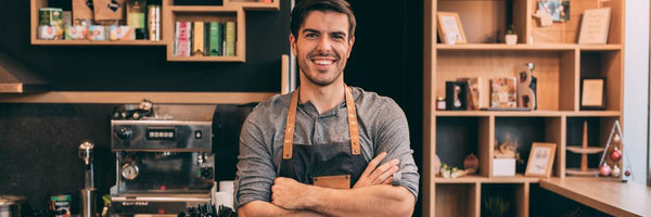 cafe owner smiling in front of coffee bar