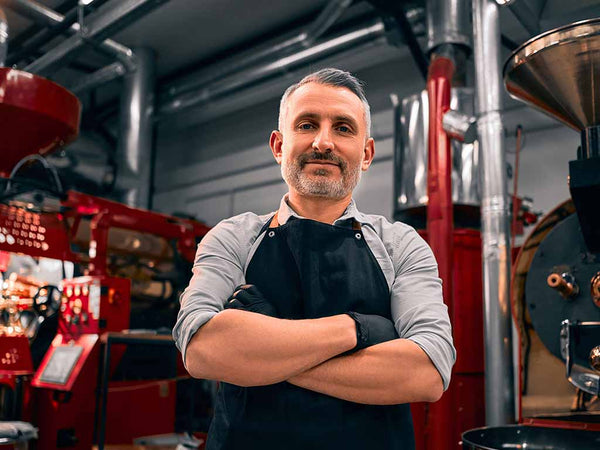 male roastmaster in front of coffee roastery equipment