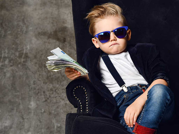 photo of boy with sunglasses in a chair holding a stack of money representing the money and financing available through Coffee Equipment Pros